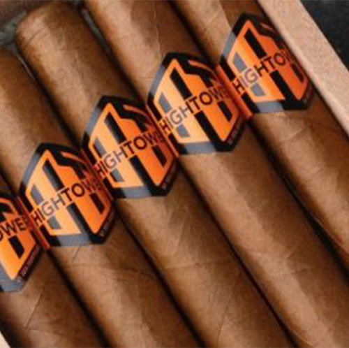 A close-up of a box of Hightower Maduro cigars neatly arranged in a wooden container. The cigars have a smooth brown wrapper and are adorned with black and orange bands featuring the Hightower logo. The premium presentation highlights the handcrafted quality of these cigars.