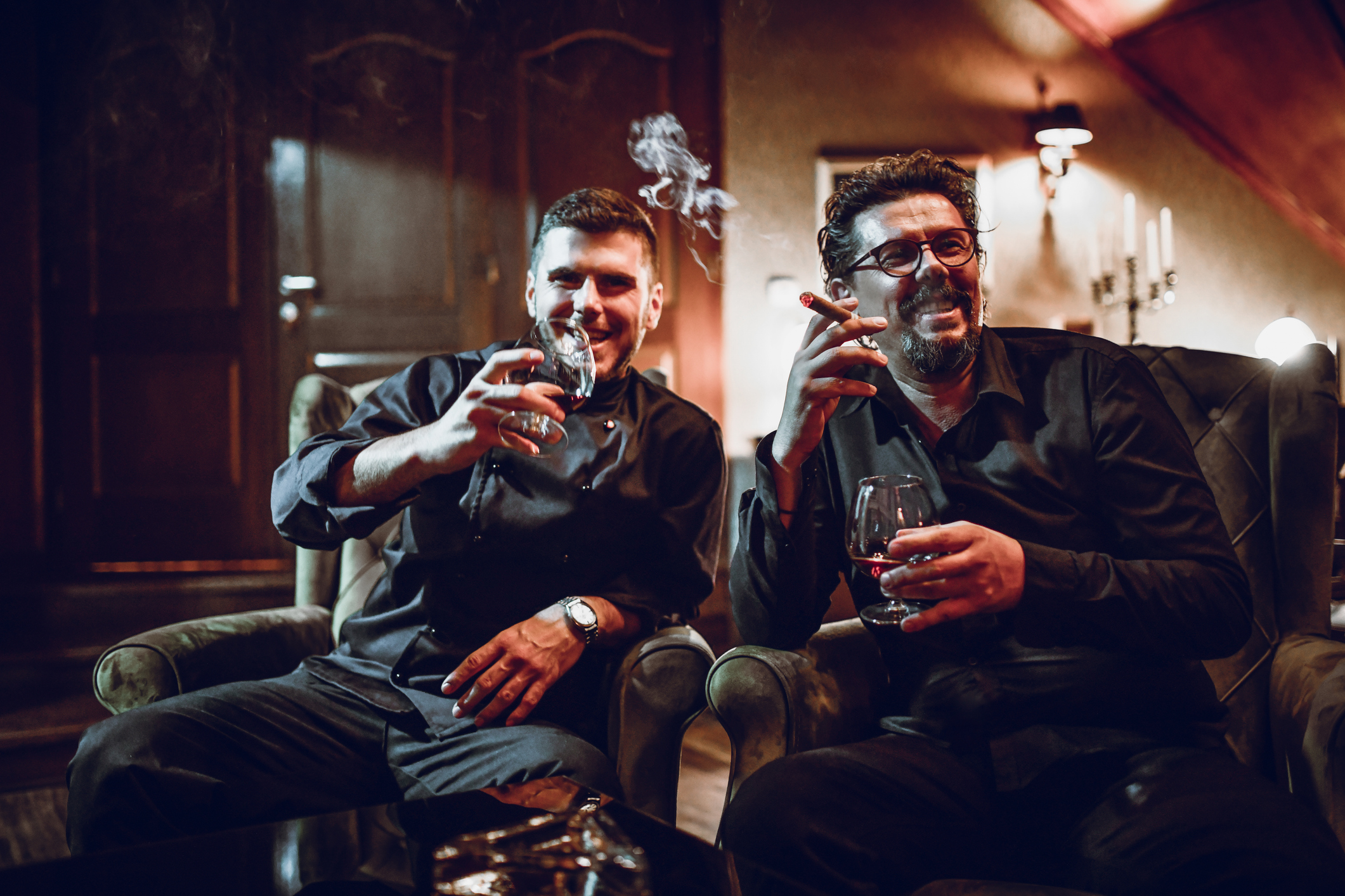 Father And Son Enjoying Rich Cigar Taste With Old Cognac